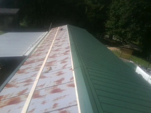 Old rusted panels beside newly installed green metal roofing — Wind Damage Roof Repair by Roofing Brothers in Kirklin