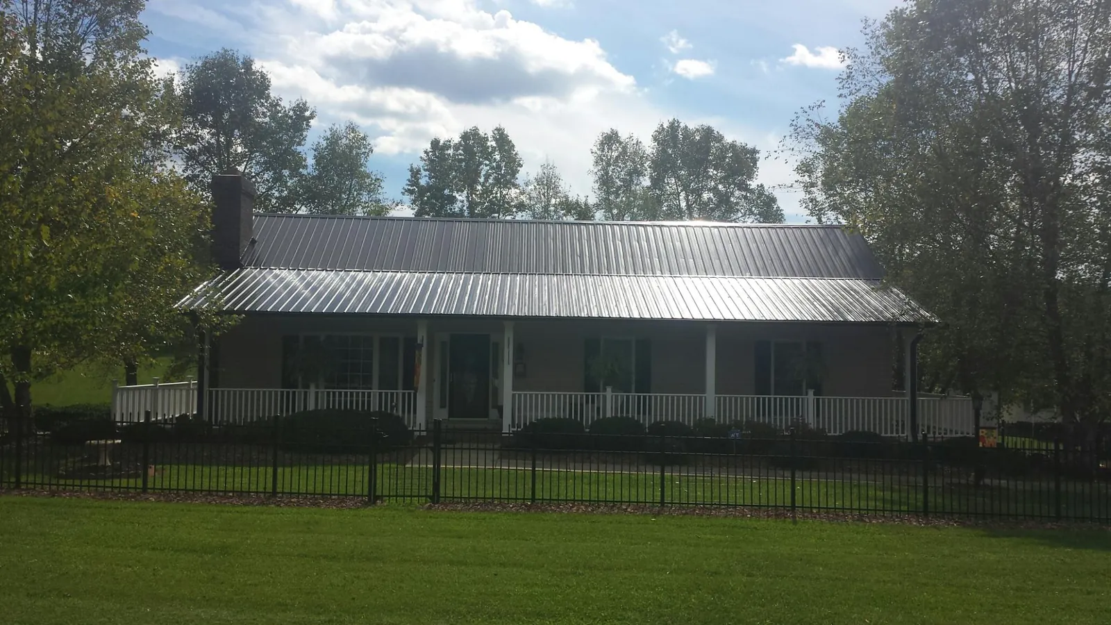 Gray metal roof on a brick ranch with a full width front porch — Gutter Guard Installation work by our crew in Kirklin