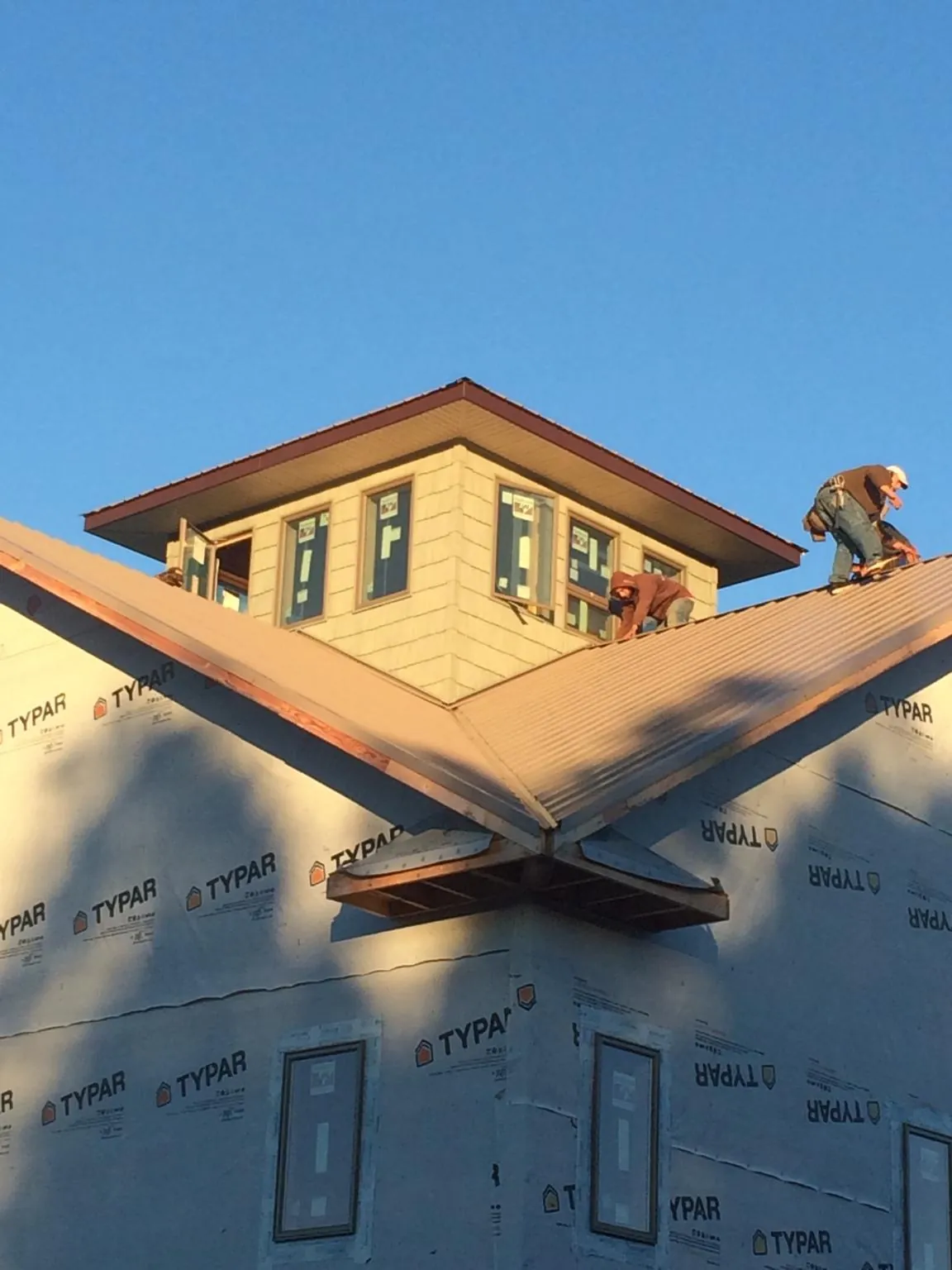 Roofers working around a rooftop cupola on a new metal roof at sunset — Roof Waterproofing in Kirklin by Roofing Brothers
